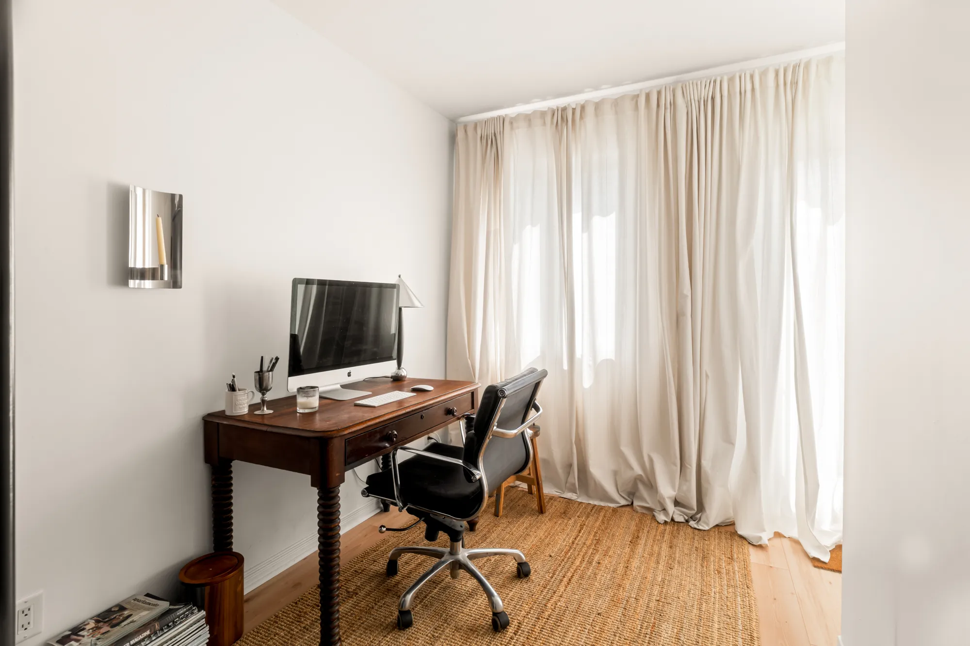 Home office with antique desk against linen curtains