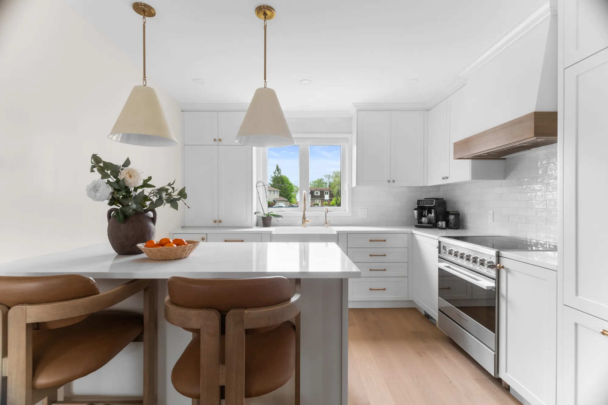 White kitchen with custom range hood and marble island